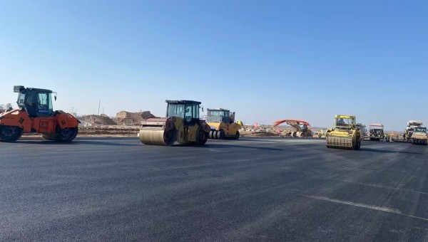 近日，在西部市政建設(shè)集團蘭州新區(qū)城市礦產(chǎn)與表面處理產(chǎn)業(yè)園區(qū)（二期）周邊基礎(chǔ)設(shè)施項目—園區(qū)西路南延段（緯五十路至緯二十八路）項目現(xiàn)場，隨著一輛輛運料車平穩(wěn)駛?cè)耄瑪備仚C將滾燙的瀝青混合料均勻鋪開，標(biāo)志著項